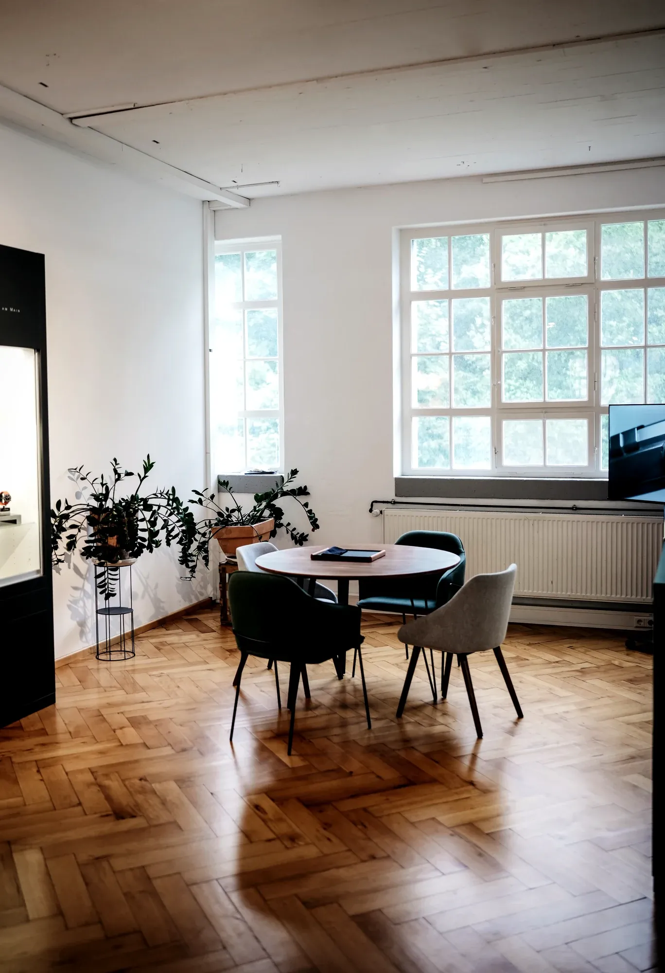 Heller Empfangsraum mit Rundtisch, Pflanzen und großem Sprossen-Fenster